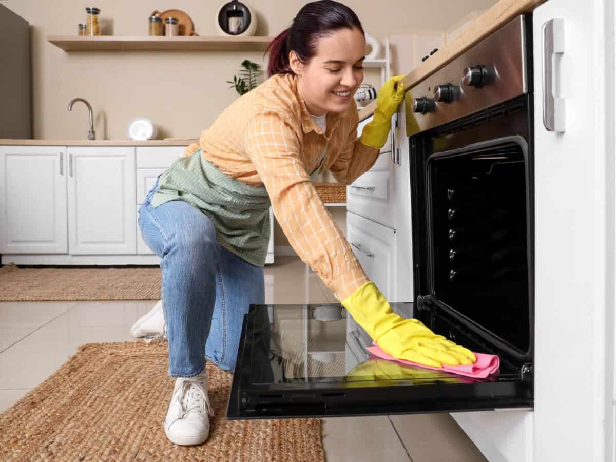 Medewerker poetst de binnenkant van een oven